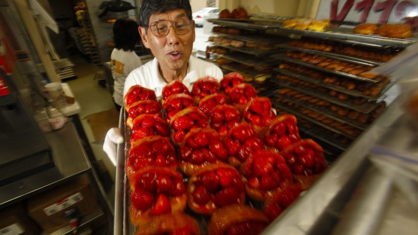 「Donut Man」創始人中野(Jim Nakano)於2011年端著一盤草莓甜甜圈。這家受到歡迎的商店將於明年擴展至大中央市場。洛杉磯時報